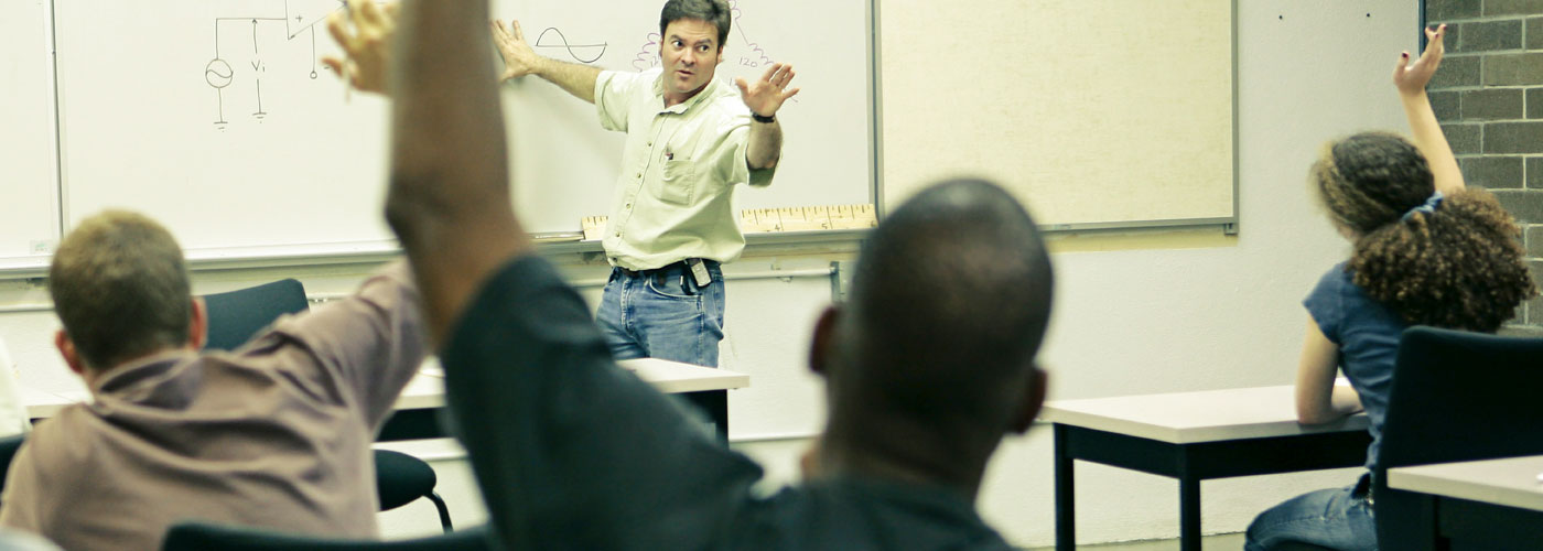 Classroom situation: young men and women with their teacher in a classroom.