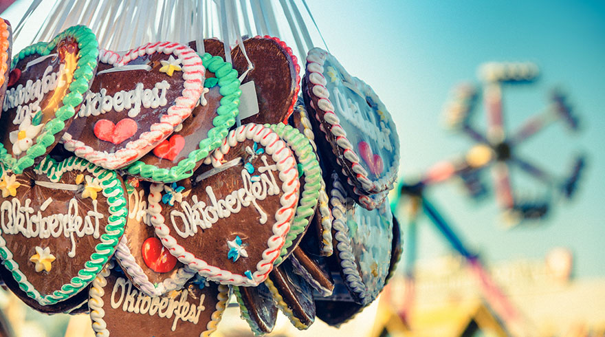 Nahaufnahme: Viele Lebkuchenherzen auf dem Oktoberfest. Im Hintergrund ein Karussell.