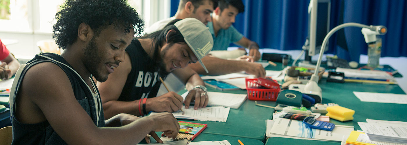 Une salle de cours : des élèves écrivent dans leur cahier.