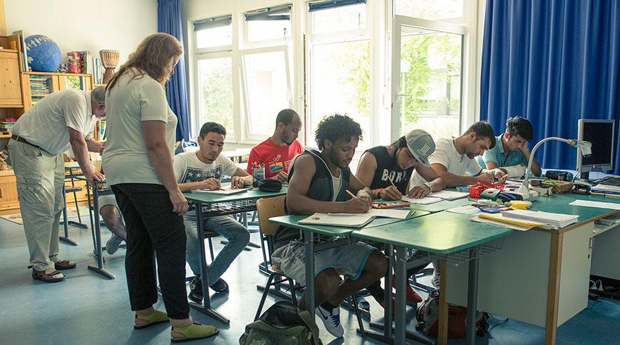 Unterrichtssituation: junge Migrantinnen und Migranten in einem Klassenzimmer.