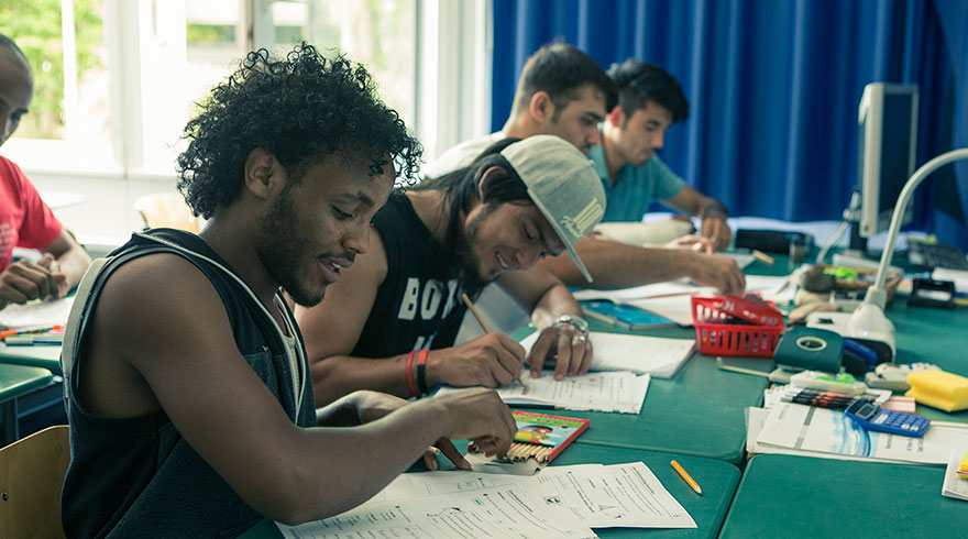 Salle de cours : des élèves écrivent dans leur cahier.