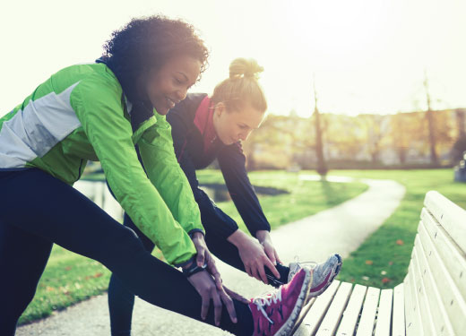 Two women exercise together in a park.