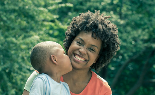 A black woman holding a child. She is smiling.