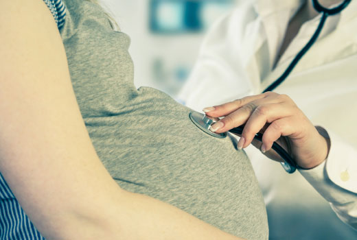 Close-up shot: the belly of a pregnant woman is examined.