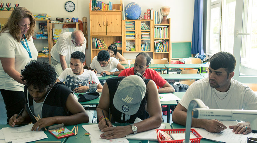 Unterrichtssituation: junge Migrantinnen und Migranten in einem Klassenzimmer.