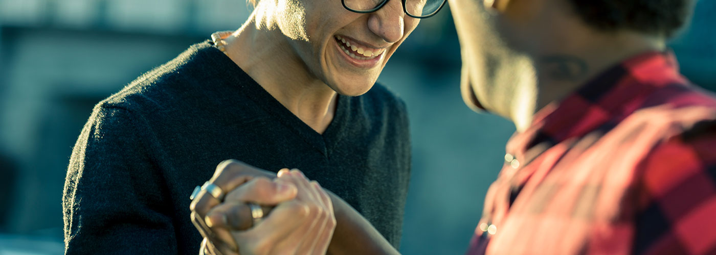 Two men exchange a friendly handshake. They are smiling.